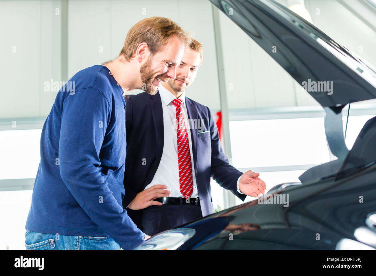 Seller or car salesman and client or customer in car dealership