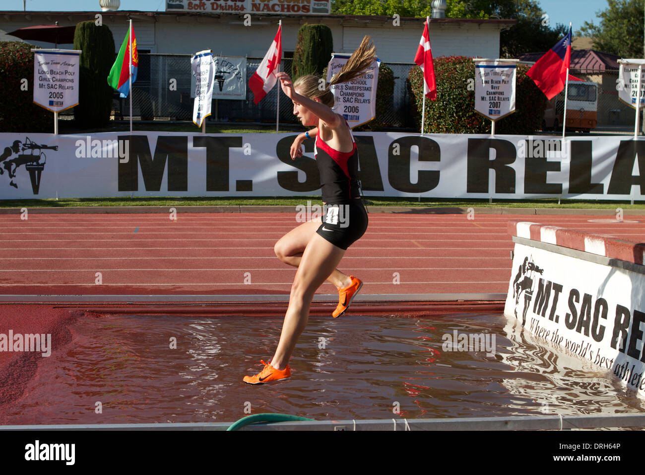 Female athletes at the water jump during a steeplechase race at an American track and field meet in California Stock Photo