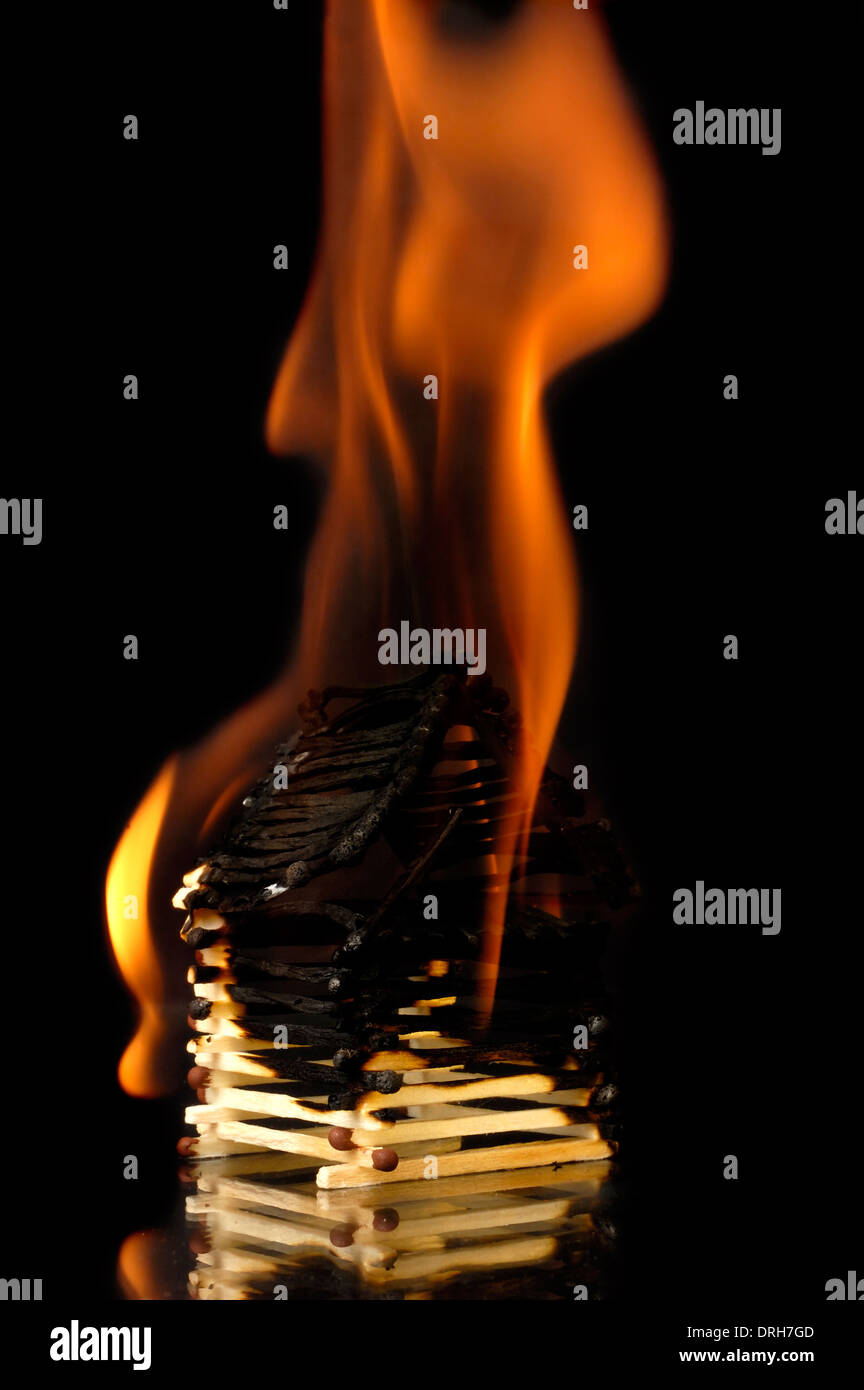 House from matches burning down with flames. Conceptual symbol isolated on black background Stock Photo