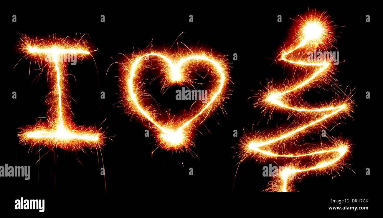 I Love Christmas, heart shape and a Christmas tree made with a sparkler light on black background Stock Photo