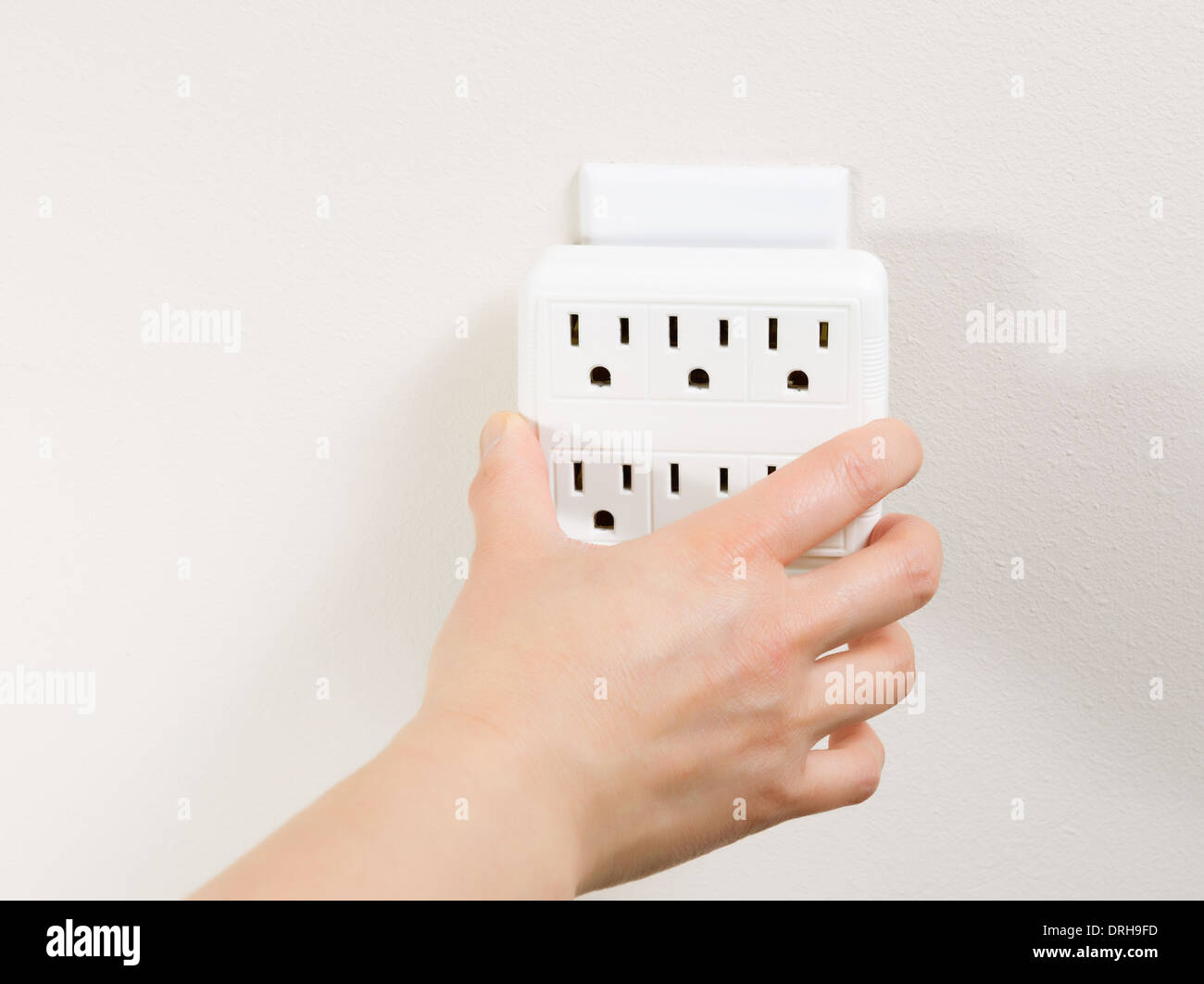 Photo of female plugging in multiple electrical socket units into wall