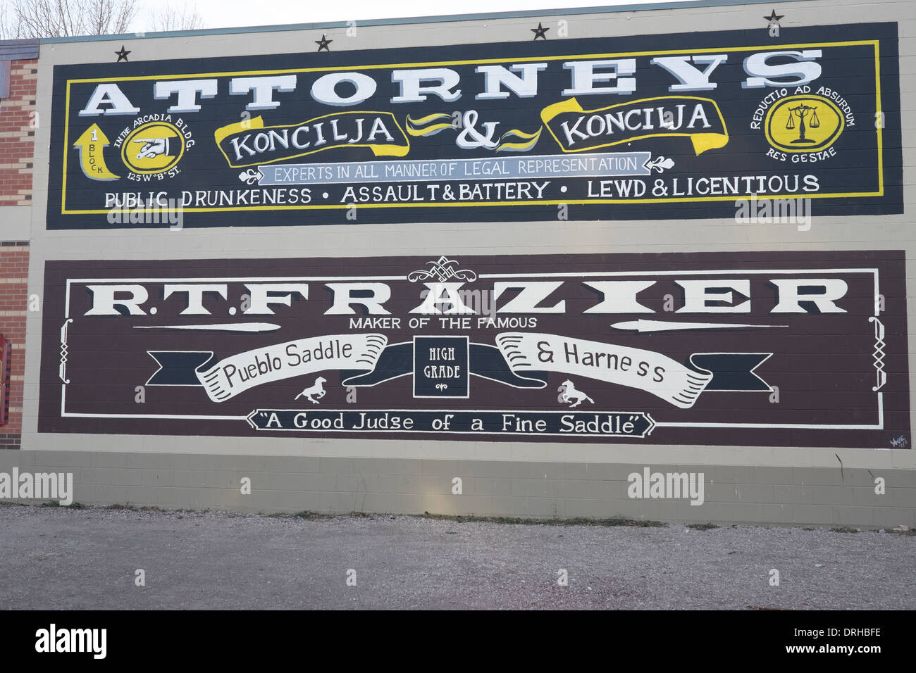 Painted advertisements on brick wall in Pueblo, Colorado. One for attorney and another for a saddle & harness company. Stock Photo
