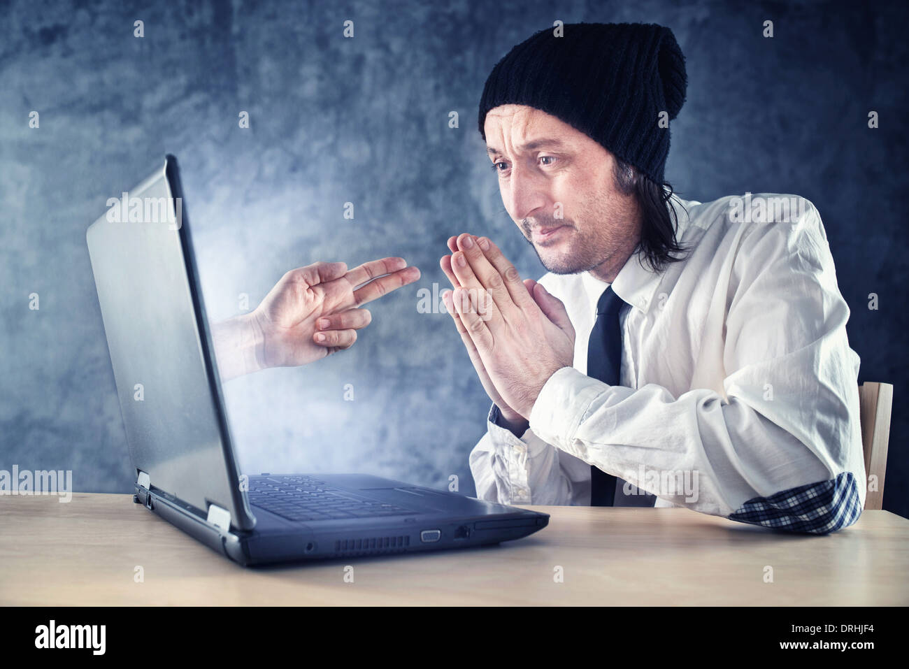 Online robbery. Businessman being robbed over internet while working on laptop computer. Stock Photo