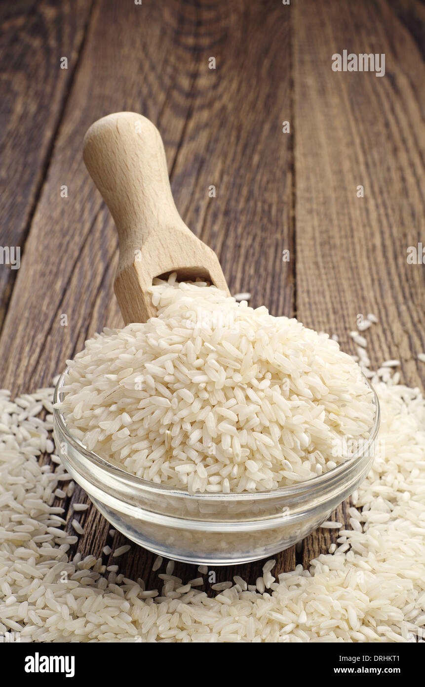 Rice in a glass bowl with a wooden spoon on the table Stock Photo