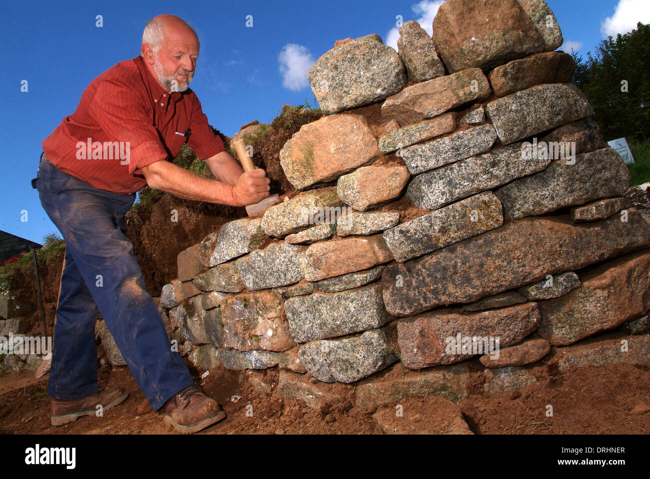 Dry stone wall builder,David Hannaforth using nothing but granite stone,which he splits from large boulders. Stock Photo