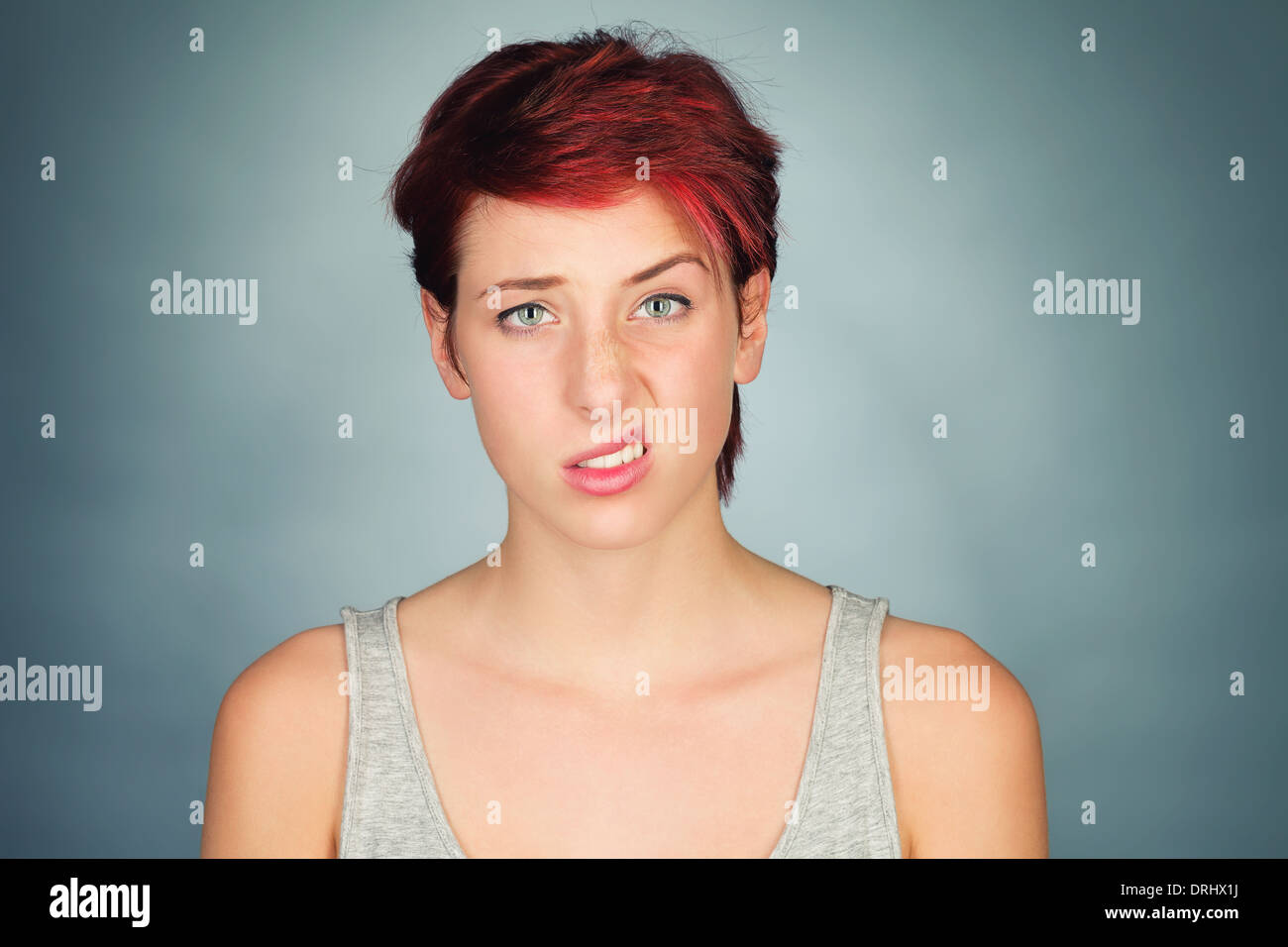 young redhead woman lifting one side of her lip and eyebrow Stock Photo
