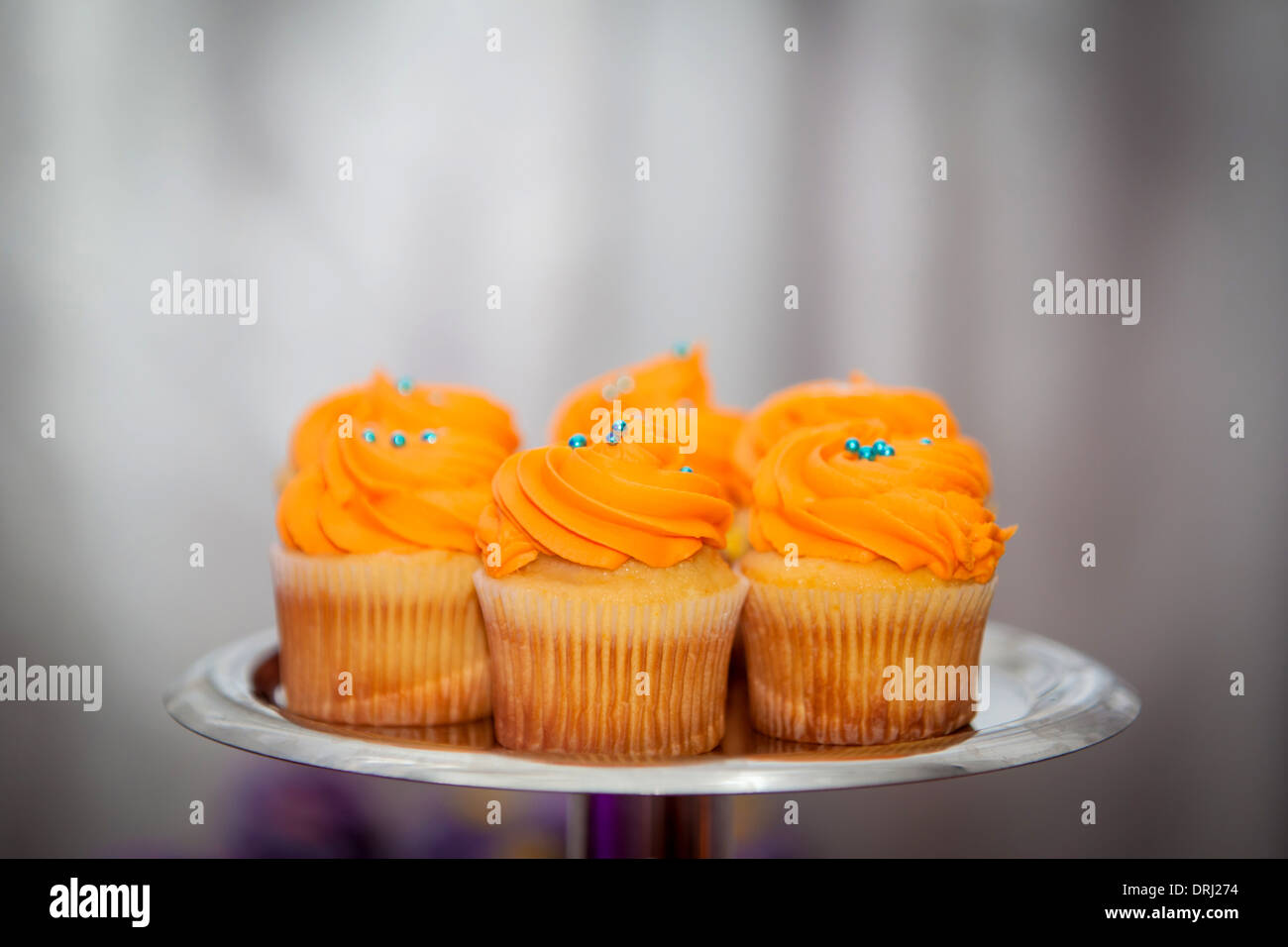 Creamy orange cupcakes with blue sprinkles on a platter Stock Photo Alamy
