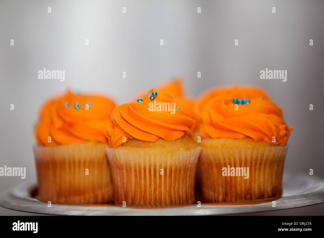 Creamy orange cupcakes with blue sprinkles on a platter Stock Photo Alamy