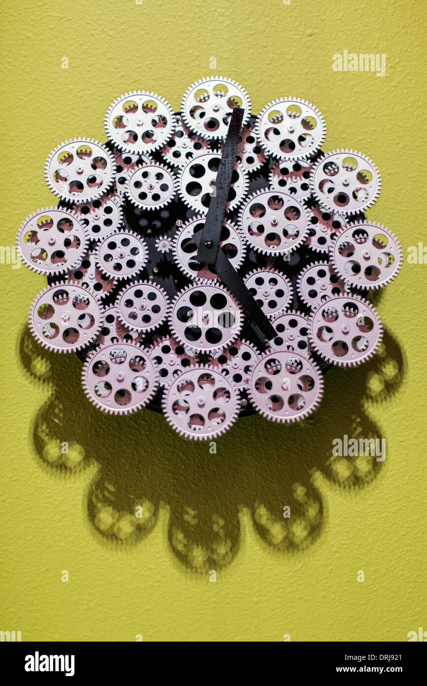 hands of a clock on a clock made up of gears on a plain wall Stock Photo