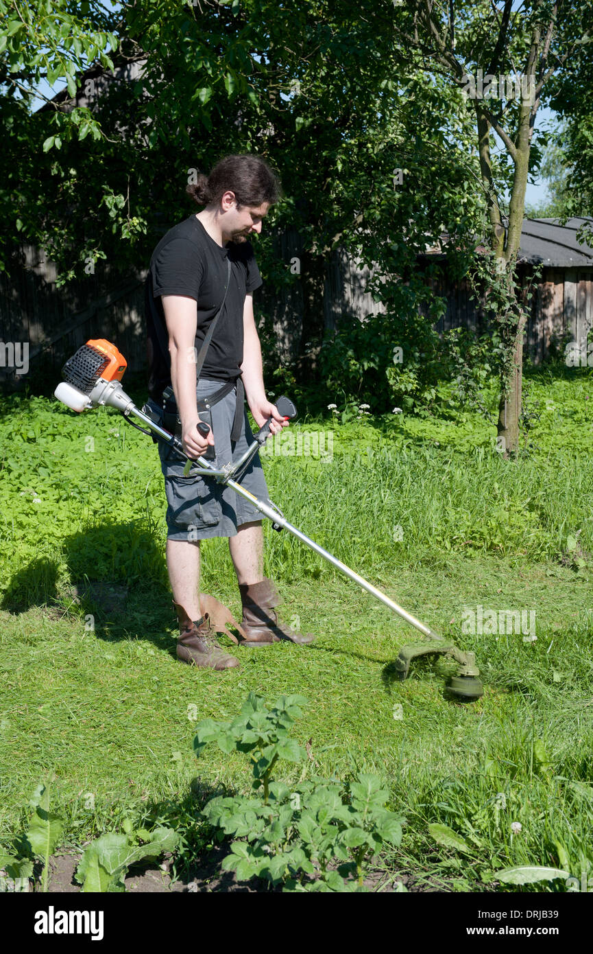 Man with a brushcutter working in a garden Stock Photo