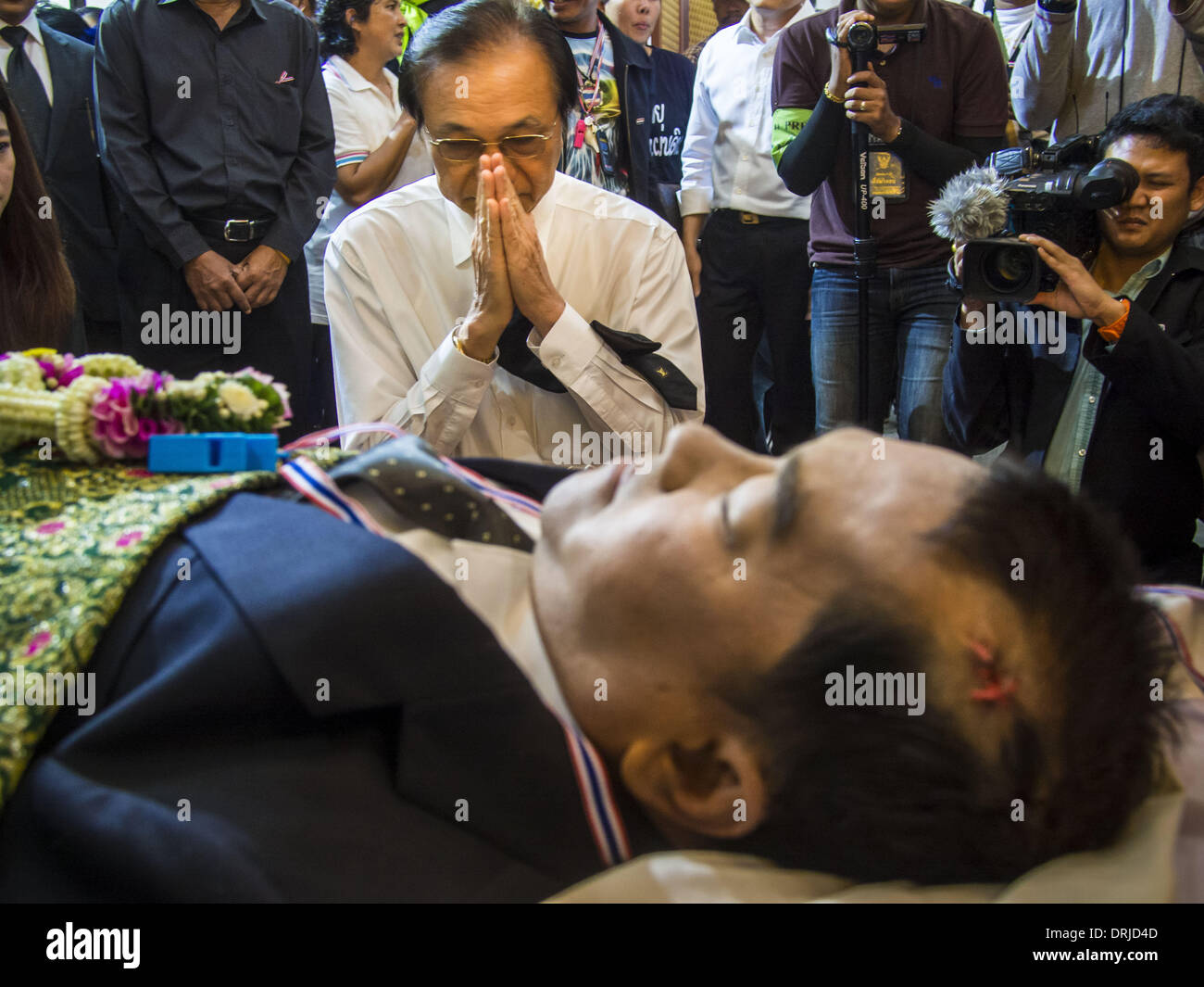 Bangkok, Thailand. 27th Jan, 2014. A man prays after pouring water during the bathing rites. Anti-government activists react to seeing the body of Suthin Taratin, with bullet wound on head, during bathing rites for Suthin at Wat Sommanat Rajavaravihara in Bangkok. Suthin was a core leader of the People's Democratic Force to Overthrow Thaksinism (Pefot), one of several organizations leading protests against the elected government of Thai Prime Minister Yingluck Shinawatra. Credit:  ZUMA Press, Inc./Alamy Live News Stock Photo