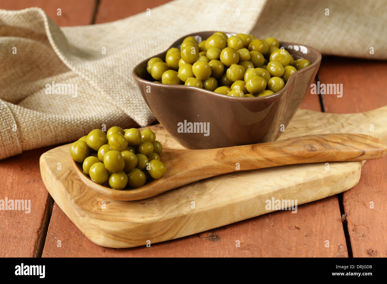 canned green peas in a wooden spoon Stock Photo