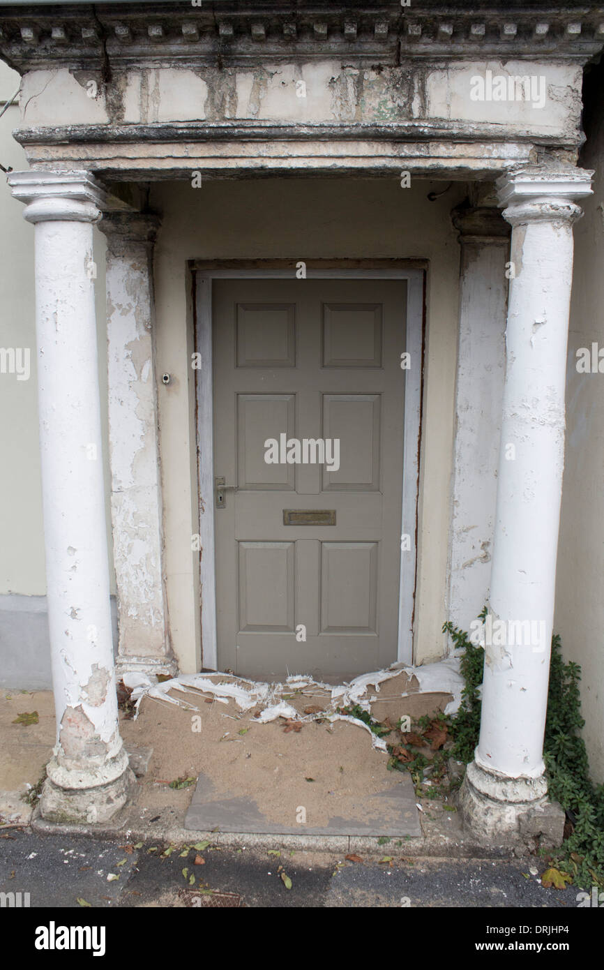 Dilapidated doorway of Georgian house with flaking paint and crumbling masonry Portico hints at former grandeur of property Stock Photo