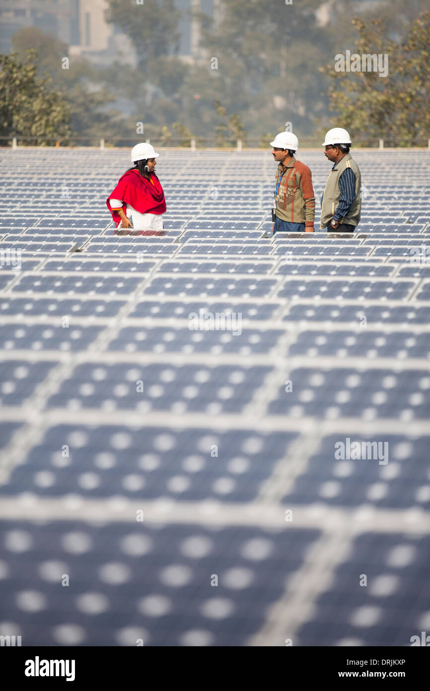 Workers at a 1 MW solar power station run by Tata power on the roof of an electricity company in Delhi, India. Stock Photo