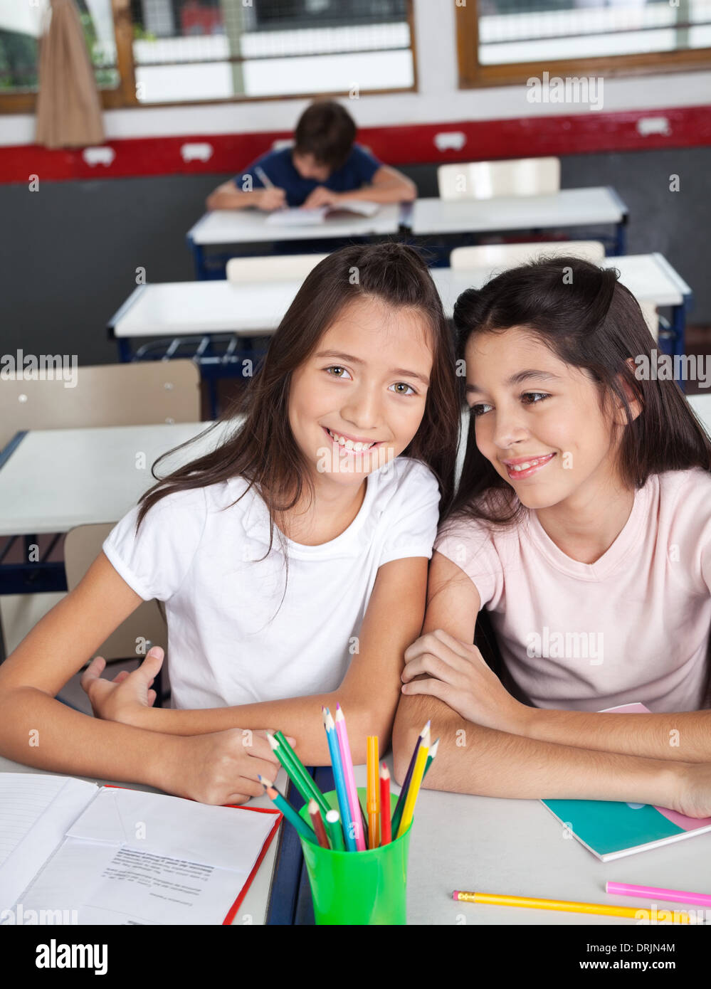 Schoolgirl Sitting With Classmate At Desk In Classroom Stock Photo - Alamy