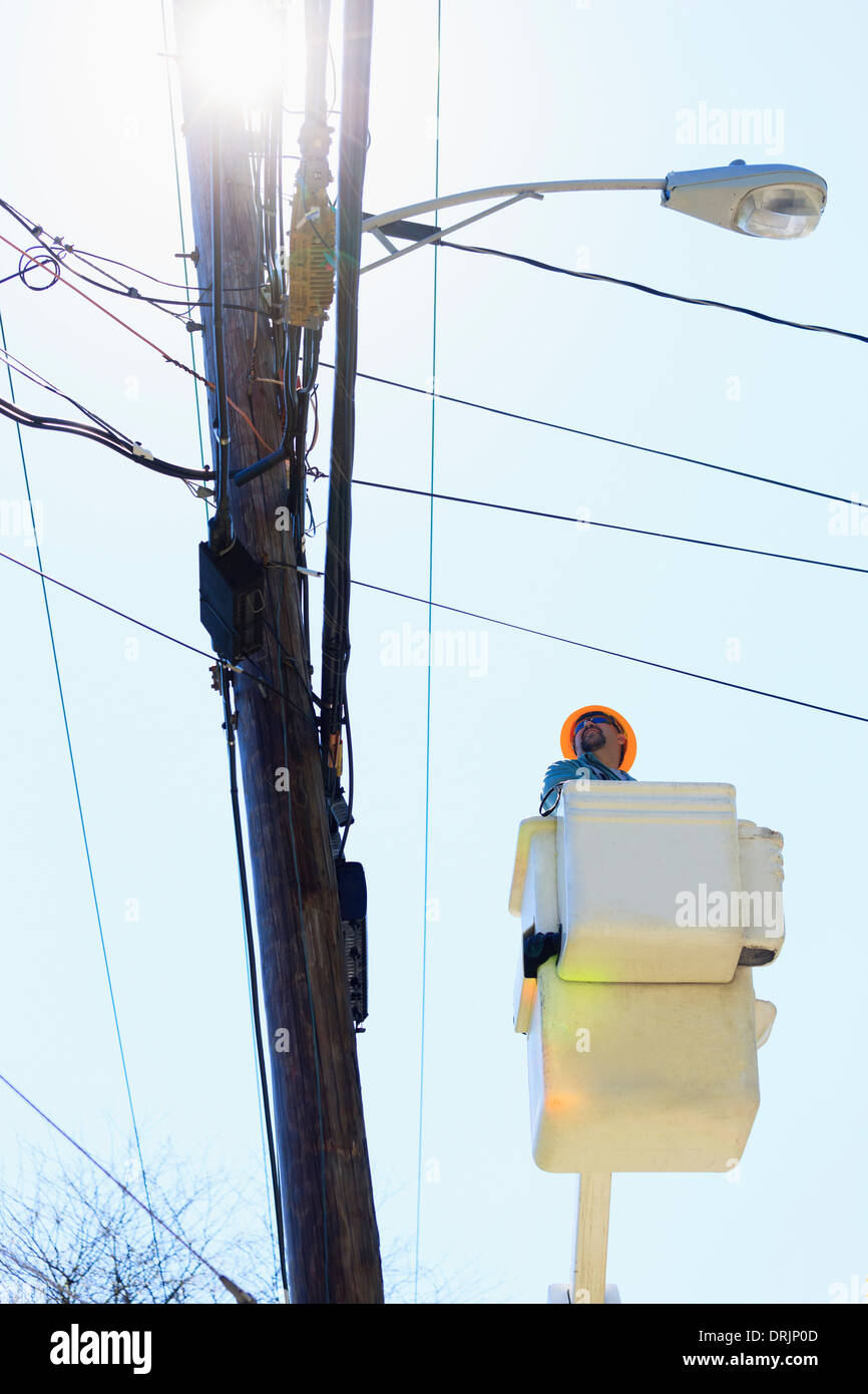 Power engineer riding in lift bucket to work on power lines, Braintree