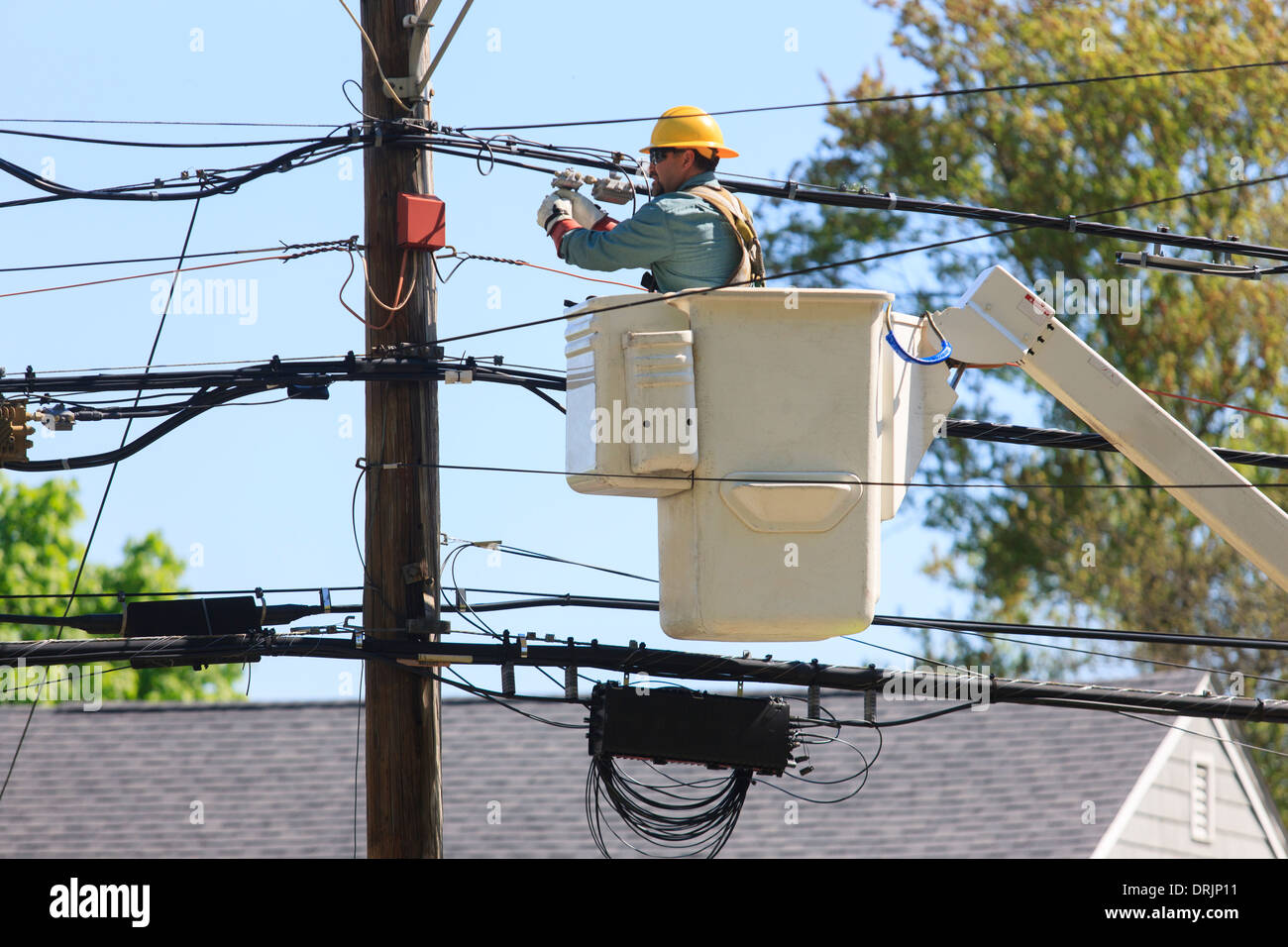 Power engineer in lift bucket working on power lines and adjusting