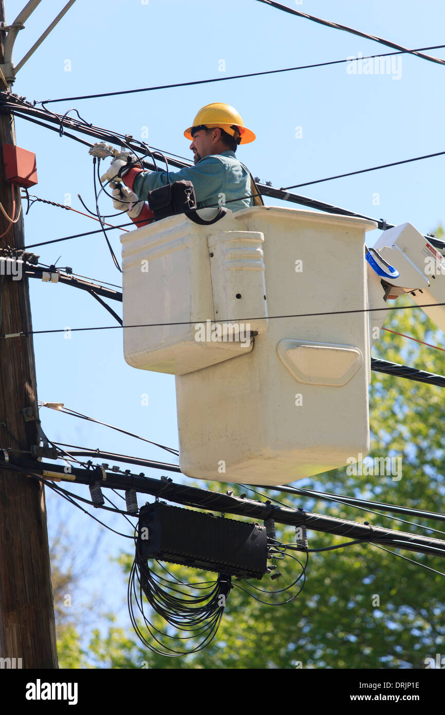 Power engineer in lift bucket working on power lines, Braintree