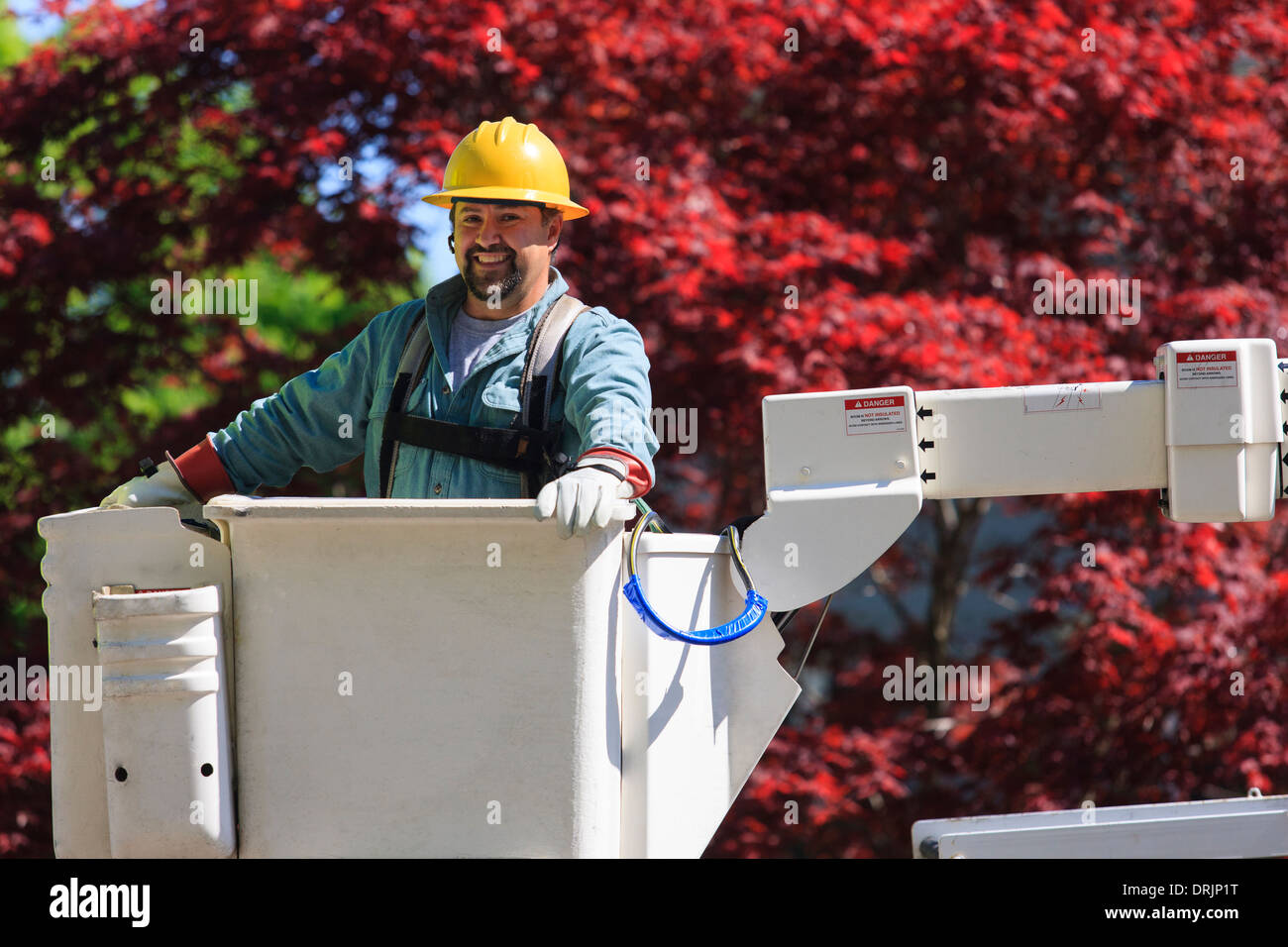 Power engineer in lift bucket wearing a safety harness and insulated