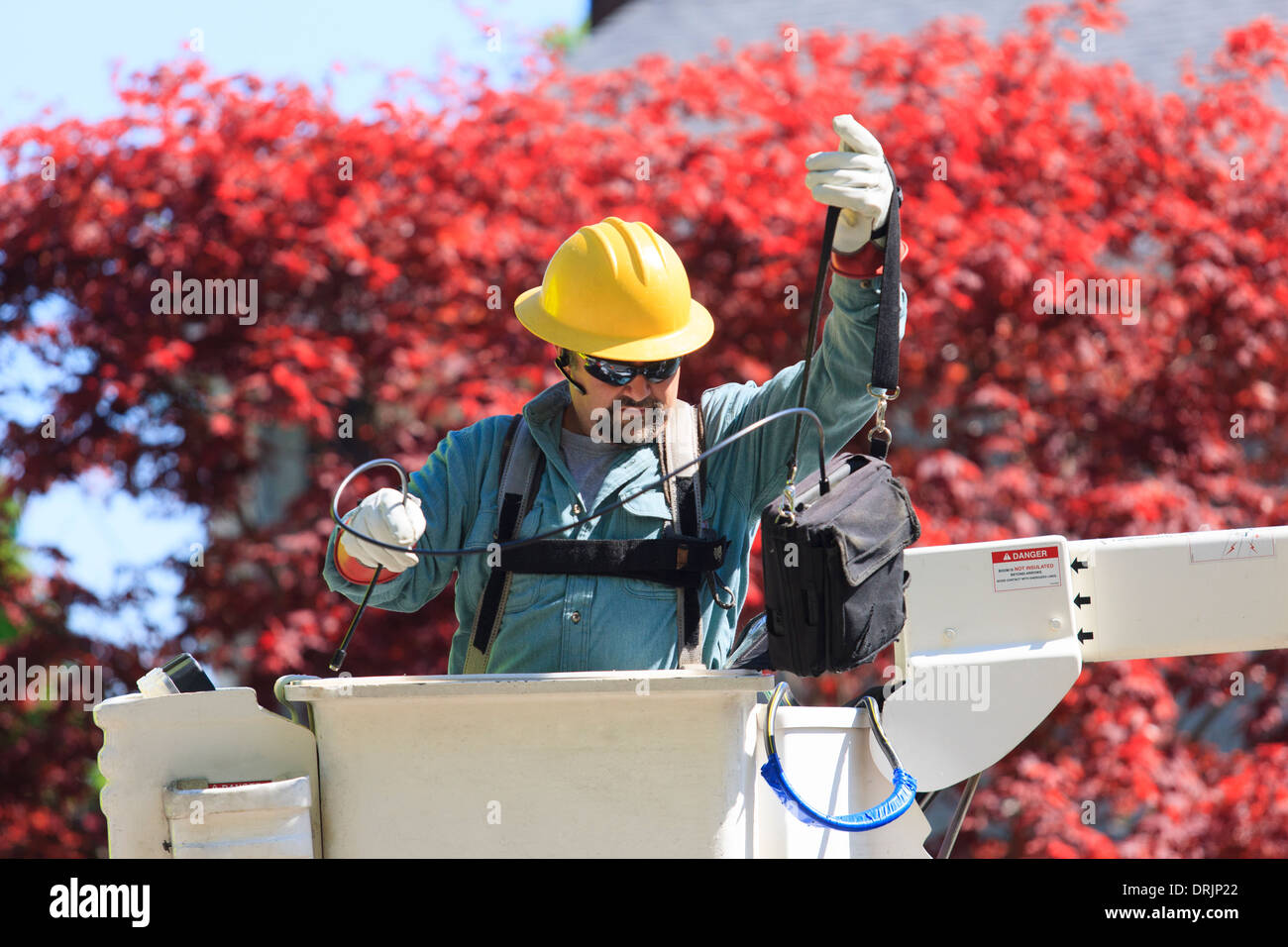 Power engineer in lift bucket working with meter to measure power