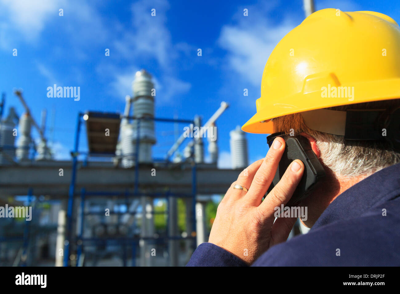 Power engineer talking on a mobile phone at high voltage distribution station, Braintree, Massachusetts, USA Stock Photo
