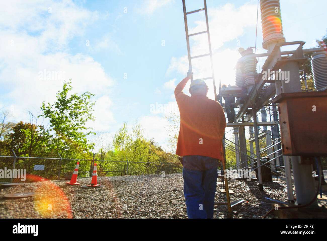 Power engineer with ladder working at high voltage power distribution