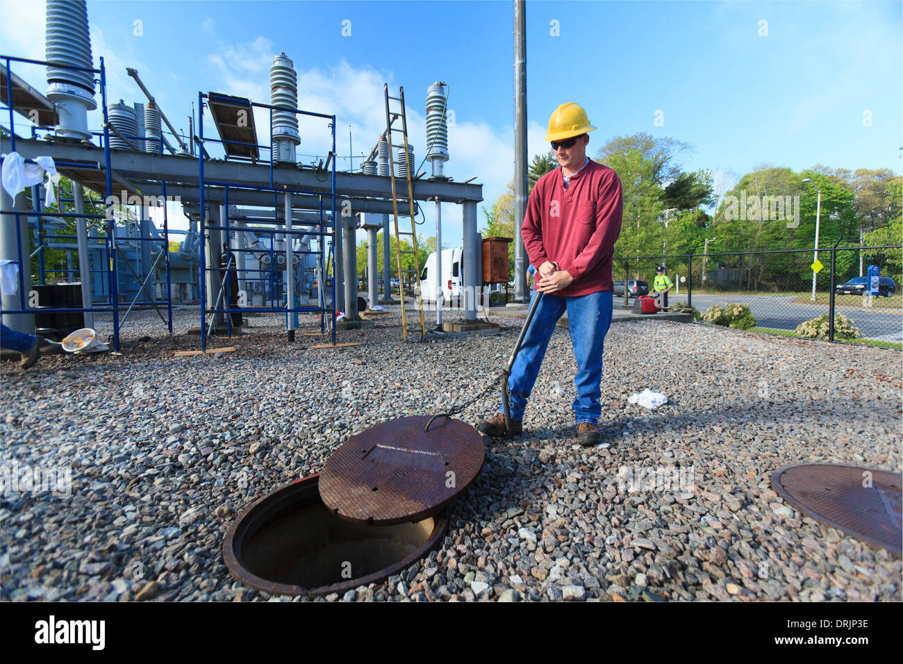 Power engineer accessing manhole cover at high voltage power