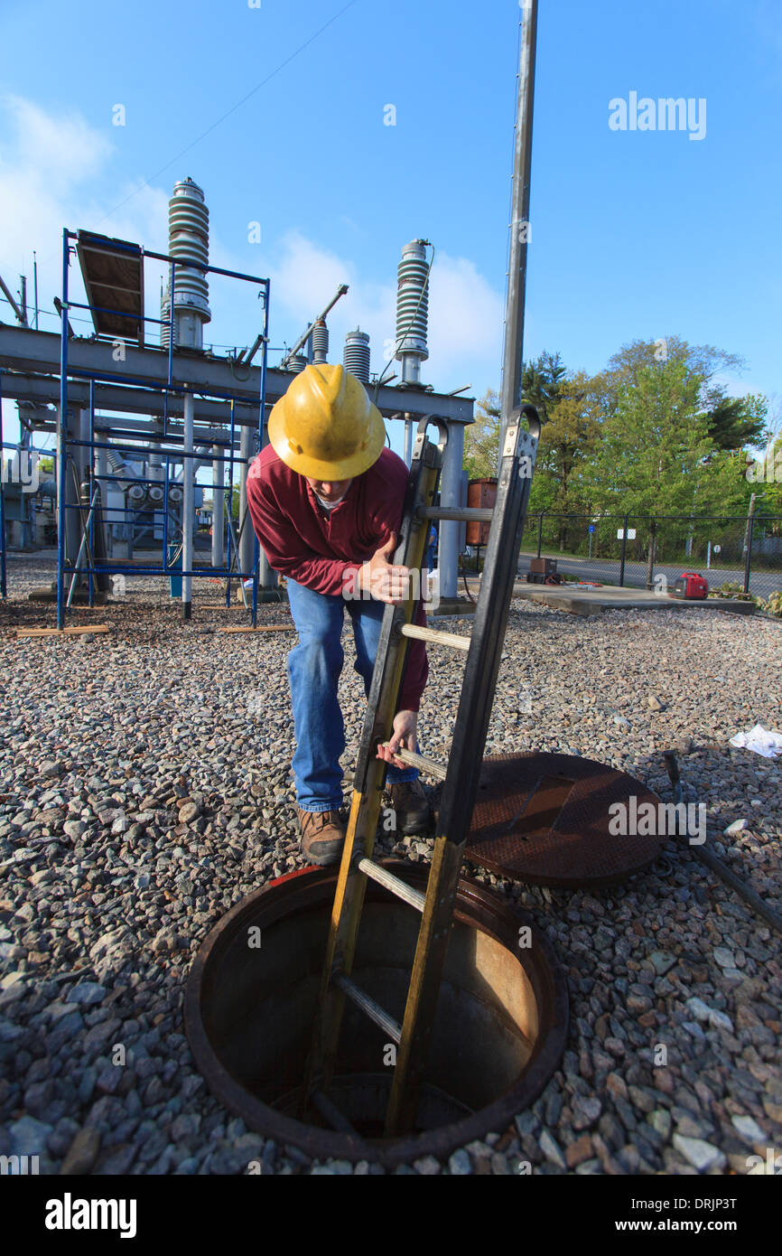Power engineer placing ladder inside manhole at high voltage power