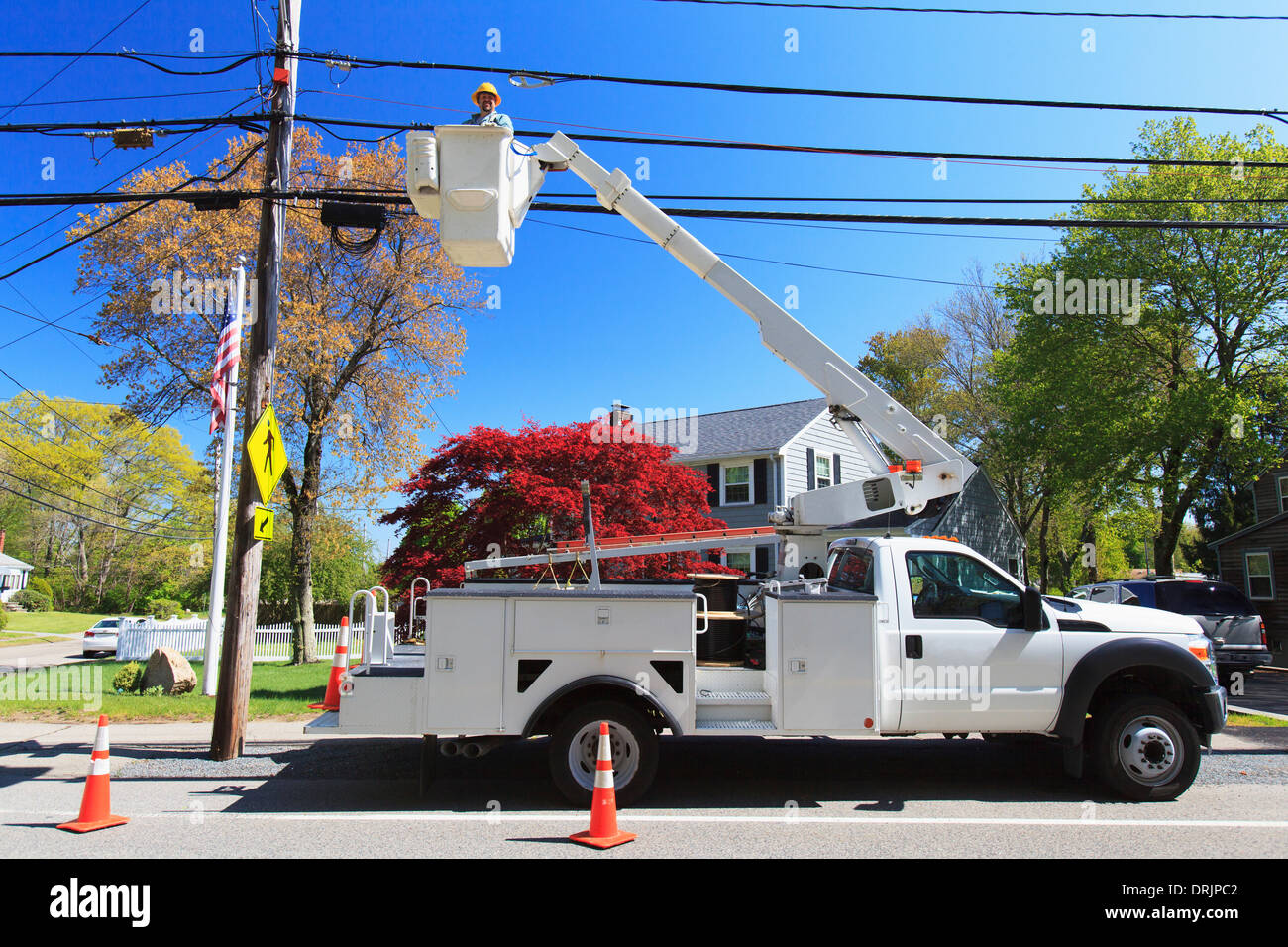 Power engineer in lift bucket working on power lines, Braintree, Massachusetts, USA Stock Photo