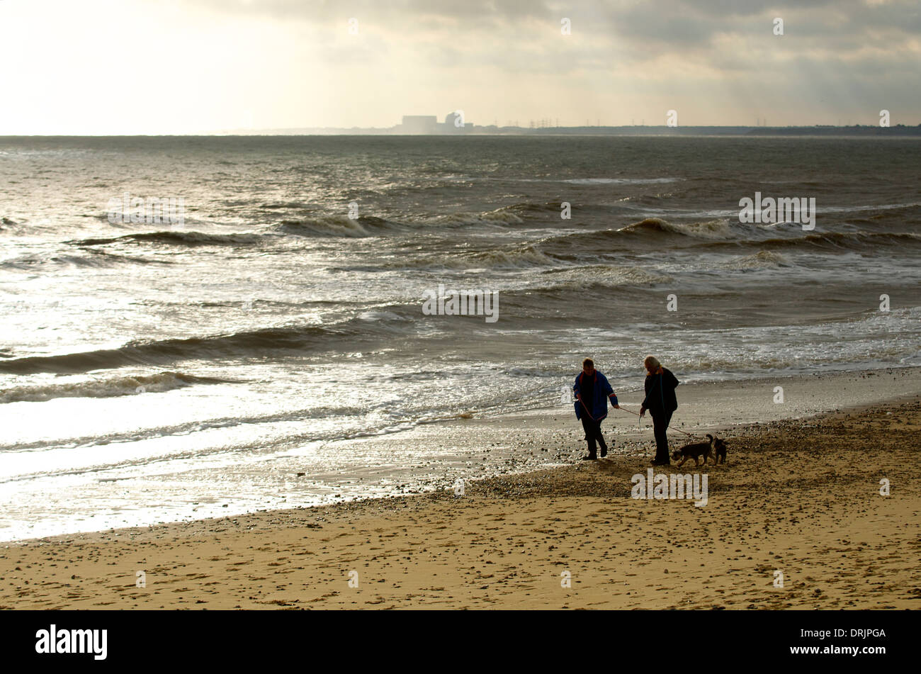 Two people walking on the beach at Walberswick with Sizewell B Nuclear Power plant in the distance Stock Photo