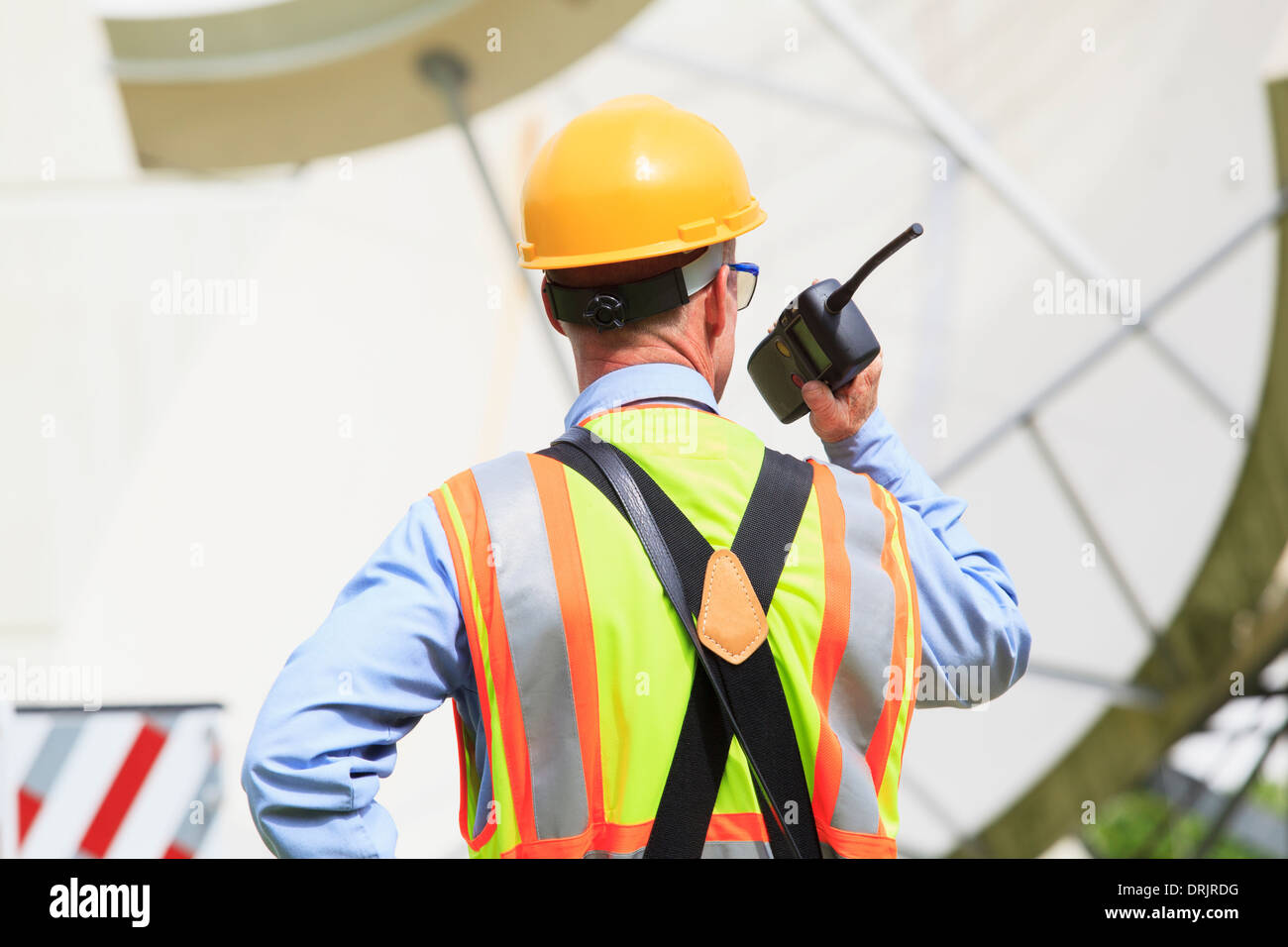 Communications engineer using walkie-talkie at satellite antenna ...
