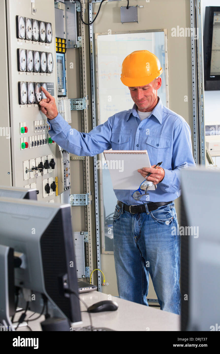 Electrical engineer inspecting power plant controls in central operations room of power plant