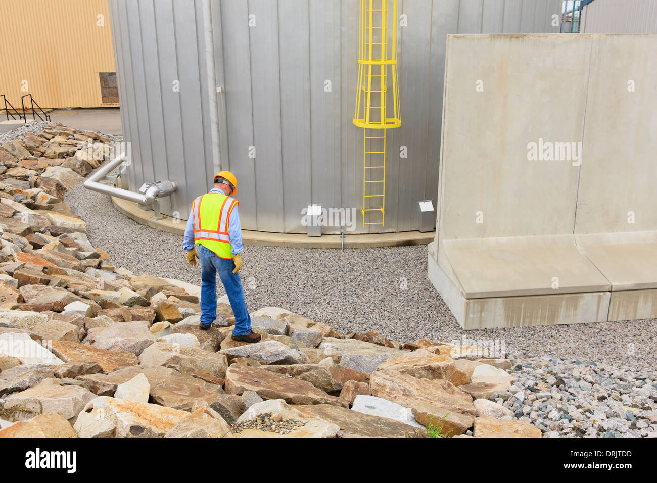 Engineer at electric power plant standing near water storage tank Stock