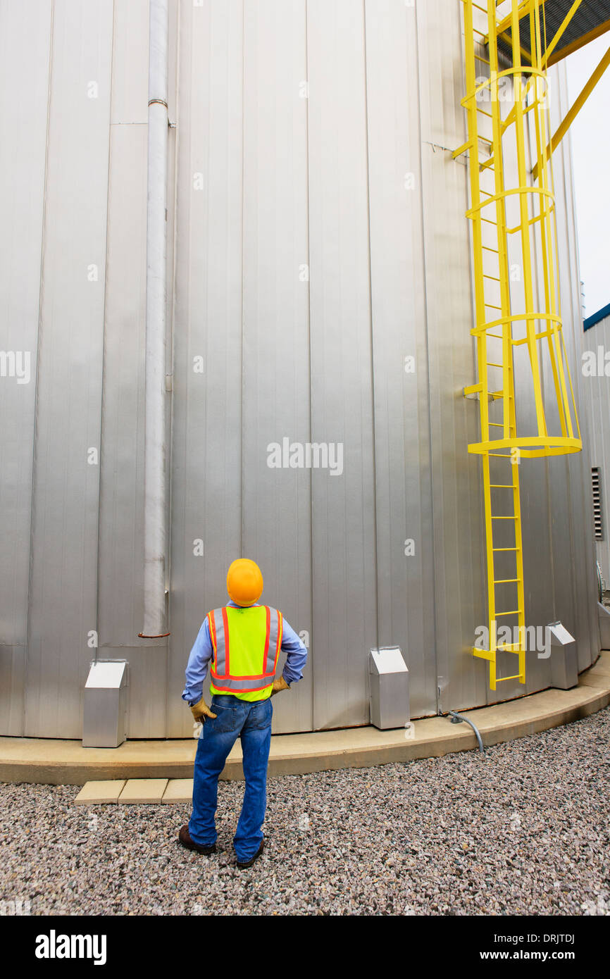 Engineer at electric power plant standing near water storage tank Stock