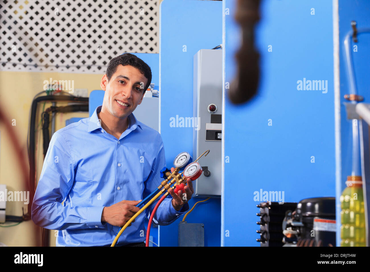 Student demonstrating air conditioner recharging manifold with gauges in HVAC classroom Stock Photo