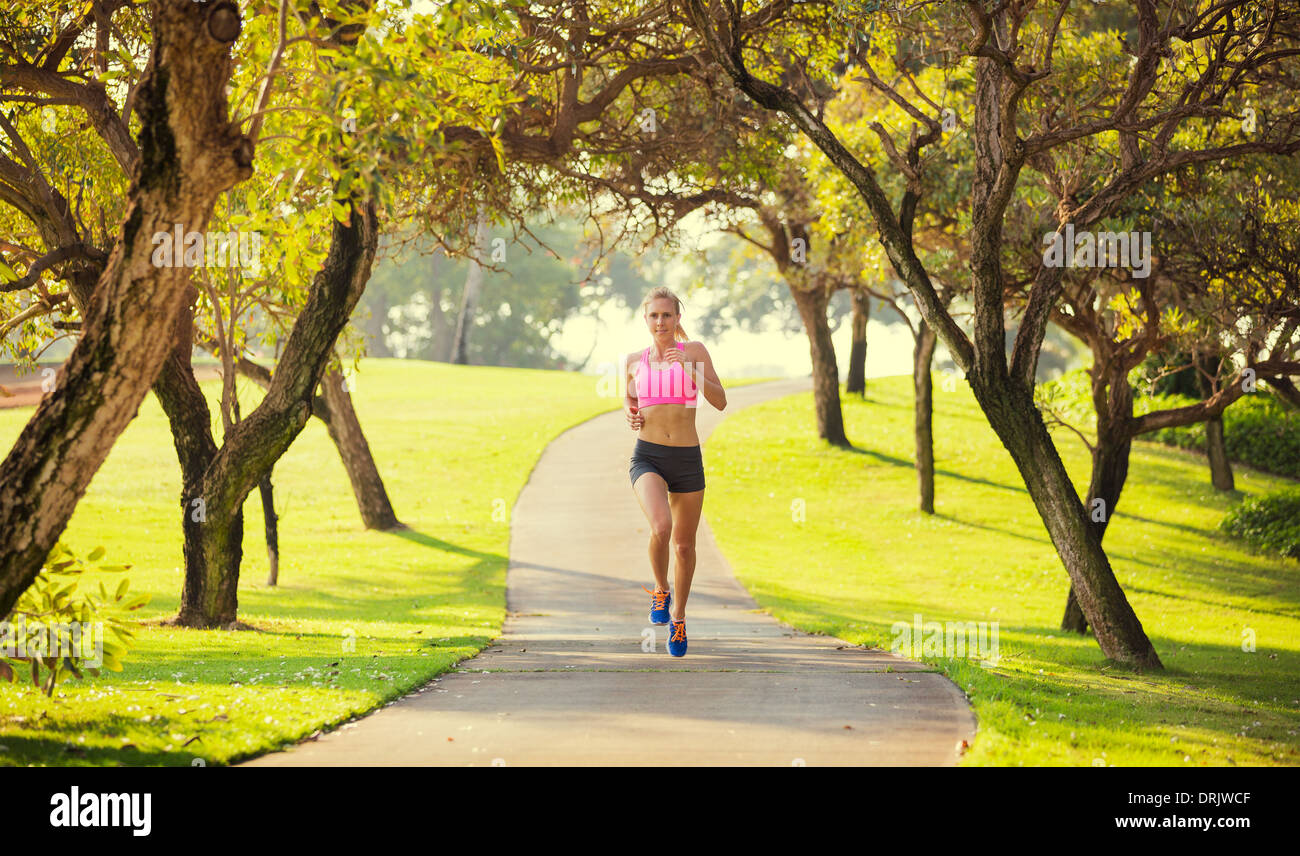 Athletic fit young woman jogging running outdoors early morning in park. Healthy lifestyle sports fitness concept. Stock Photo