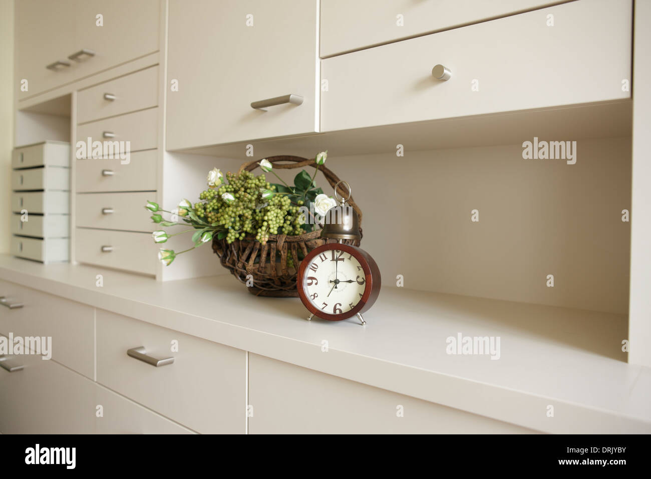 Flowers and clock on white shelf Stock Photo