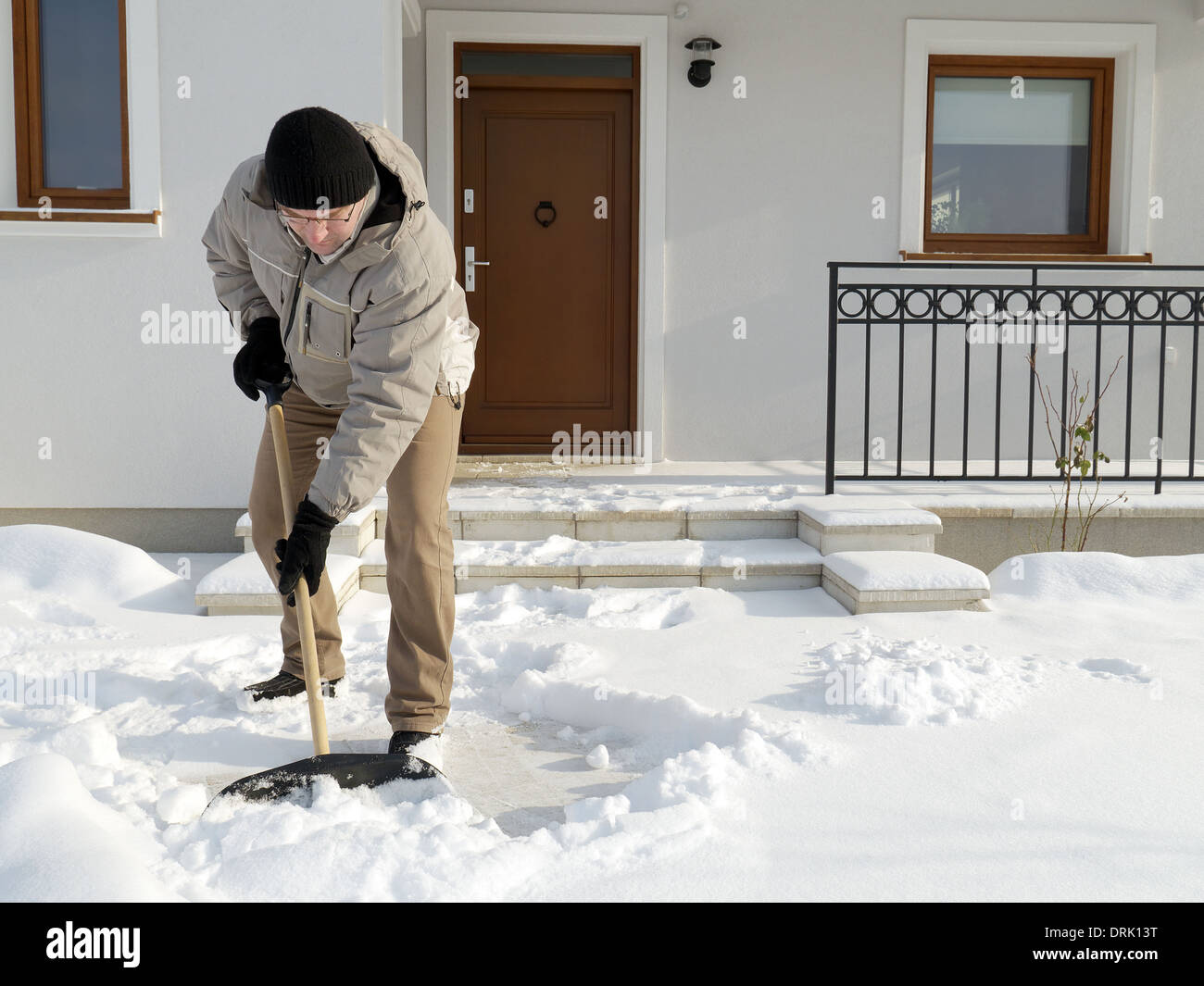 Man clearing path to his house of snow with shovel after heavy snowing Stock Photo