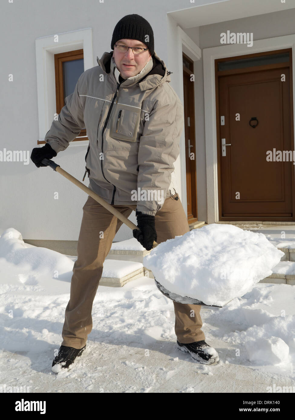 Man clearing path to his house of snow with shovel after heavy snowing Stock Photo
