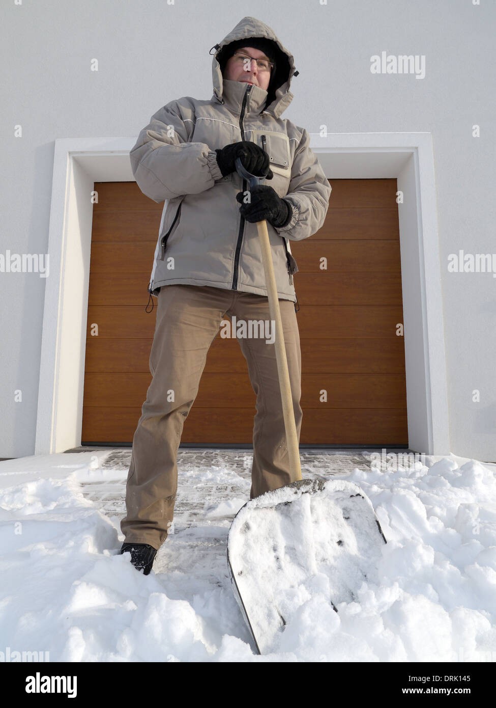 Man clearing driveway of snow with shovel after heavy snowing Stock Photo