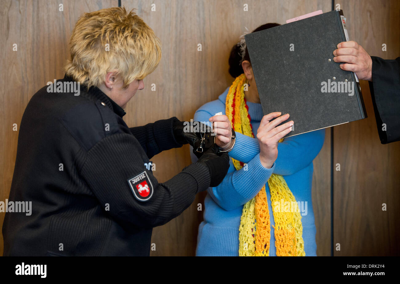 Hildesheim, Germany. 28th Jan, 2014. A judicial officer removes the handcuffs of defendant Evgeniya C. at the district court in Hildesheim, Germany, 28 January 2014. The woman is on trial for the death of her baby. She is accused of giving birth to a boy on her toilet and then repeatedly flushing it. It remains uncertain whether the baby was still alive at birth. Photo: Julian Stratenschulte/dpa/Alamy Live News Stock Photo