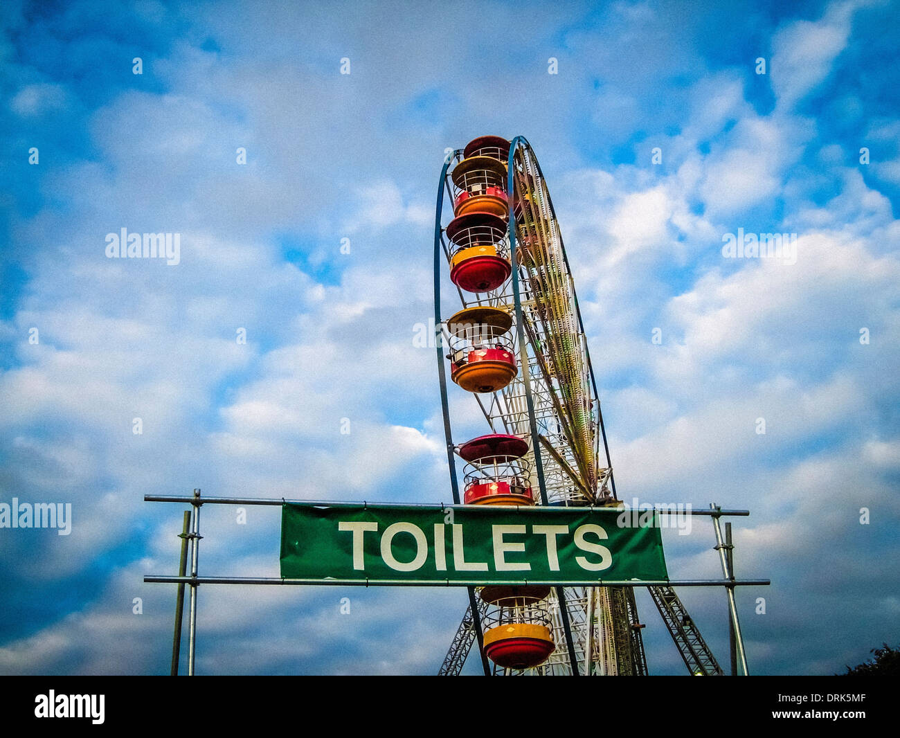 Big wheel fairground ride and Toilets sign at music festival Stock Photo