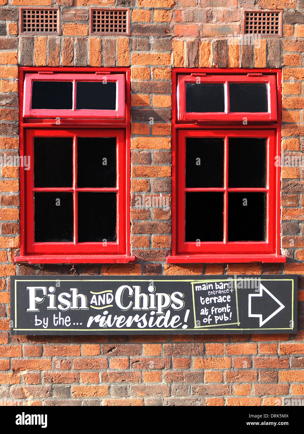 wooden arrow sign with the text Fish and chips on the red brick house Stock Photo
