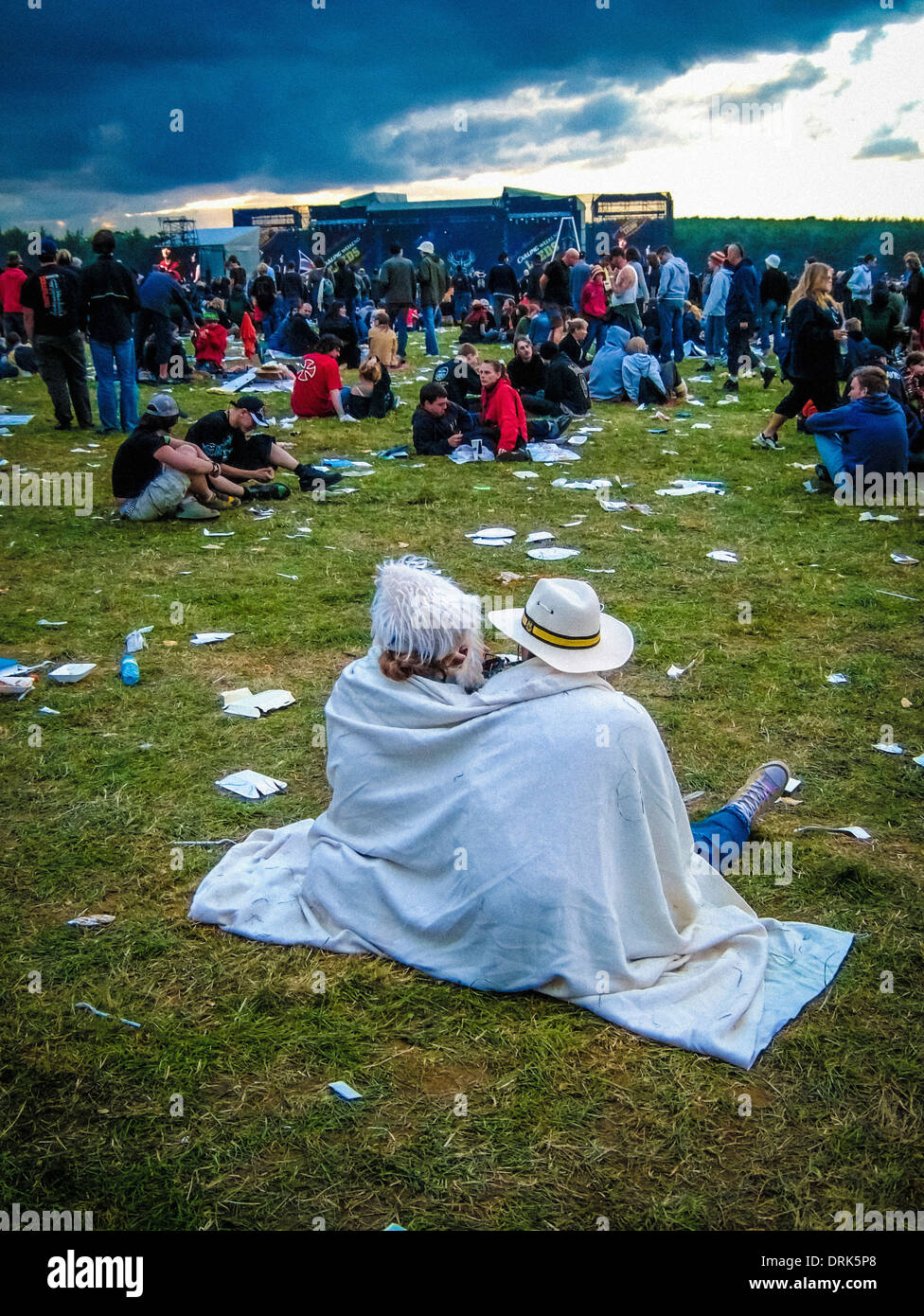 Couple wrapped in blanket, watching a performance, keeping warm at a music festival. UK Stock Photo
