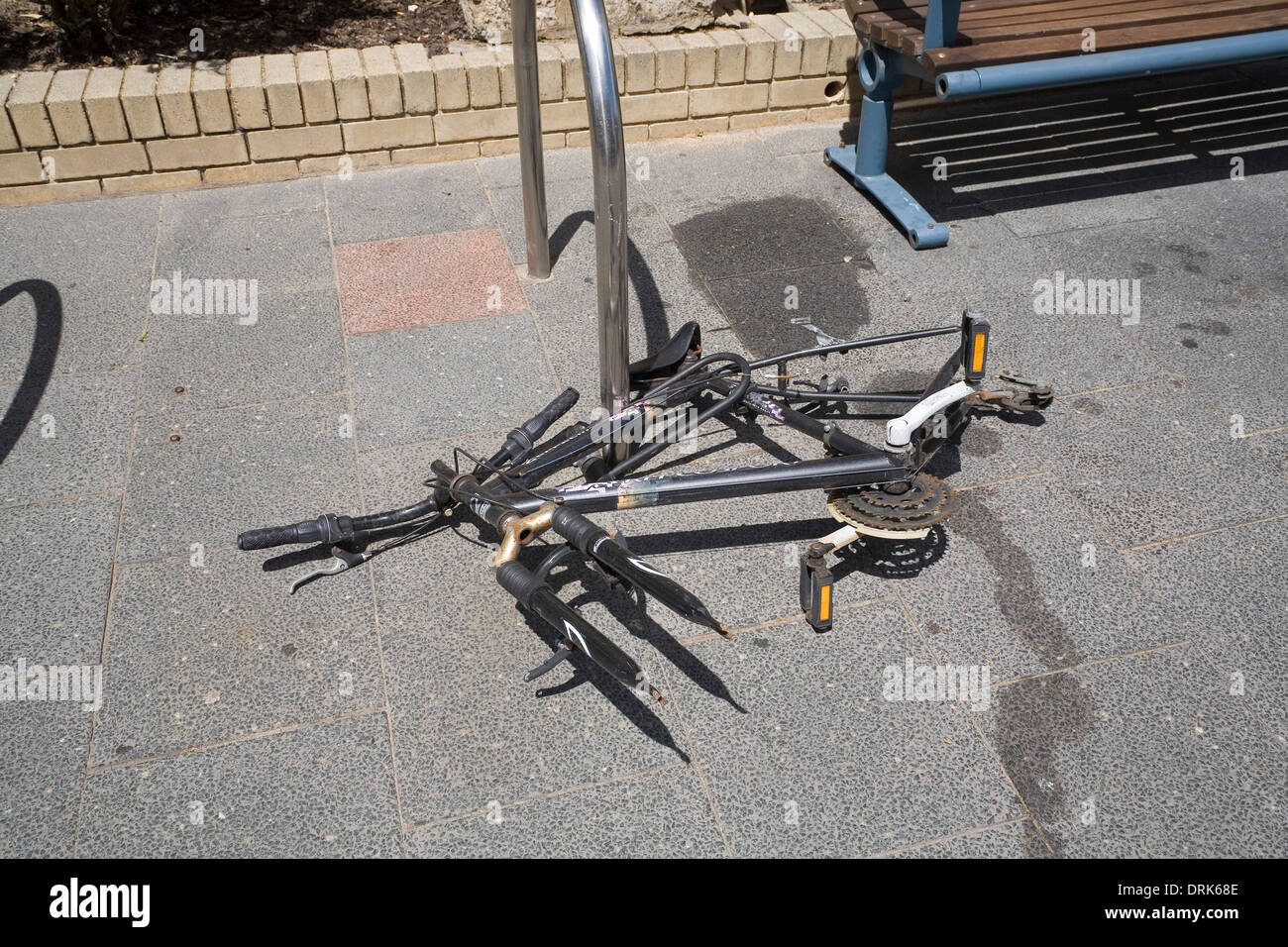 Bicycle padlocked to a bicycle stand, but with its wheels stolen, no