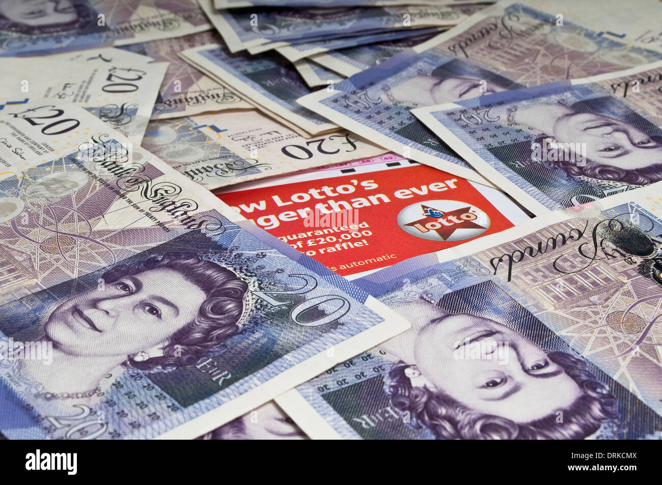 Lottery ticket in the middle of a pile of scattered twenty pound notes Stock Photo
