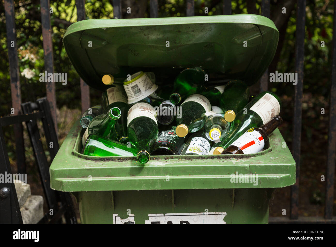 Green glass recycling bin full of bottles Stock Photo