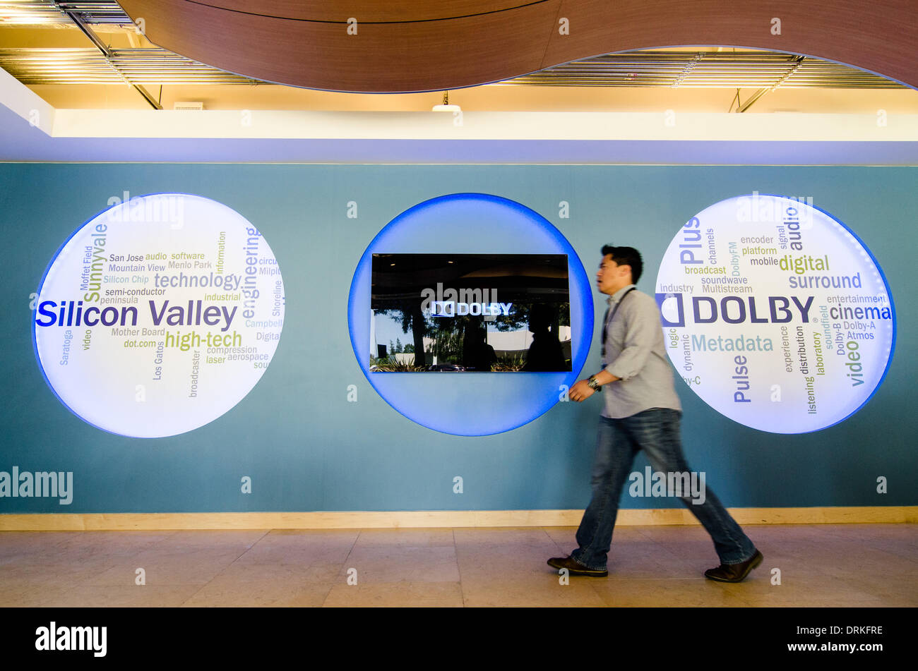 An employee walks past the Dolby logo at the company's laboratory in Sunnyvale, CA (opened 2012). In the heart of Silicon Valley, engineers work on technologies like 3D without glasses (Dolby 3D), surround sound for conference calls (Dolby Voice) and new - Stock Photo