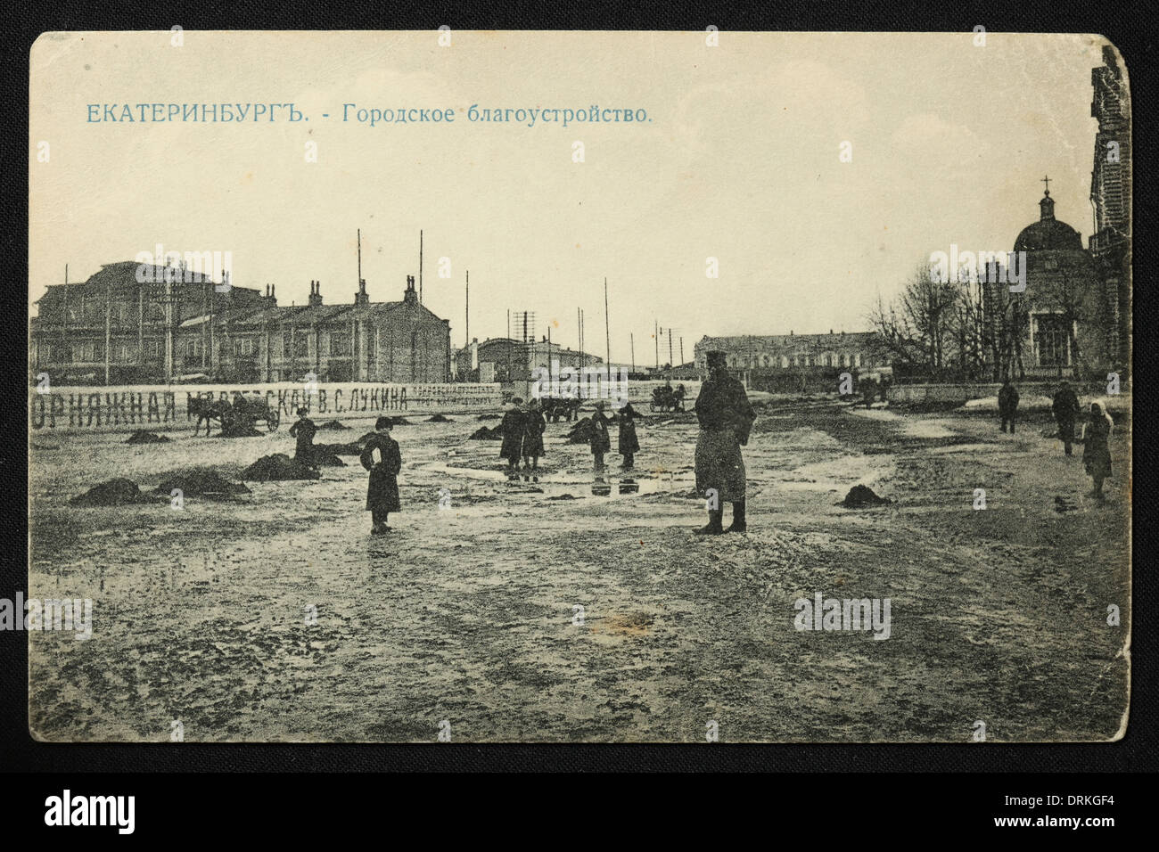 Mud and puddles in the Cathedral Square also known as the Market Square in Yekaterinburg, Russian Empire. Black and white vintage photograph by Russian photographer Nikolai Vvedensky dated from the beginning of the 20th century issued in the Russian vintage postcard published by M.S. Semkov, Yekaterinburg. Photo by Nikolai Vvedensky. Text in Russian: Yekaterinburg. Urban Beautification. Courtesy of the Azoor Postcard Collection. Stock Photo