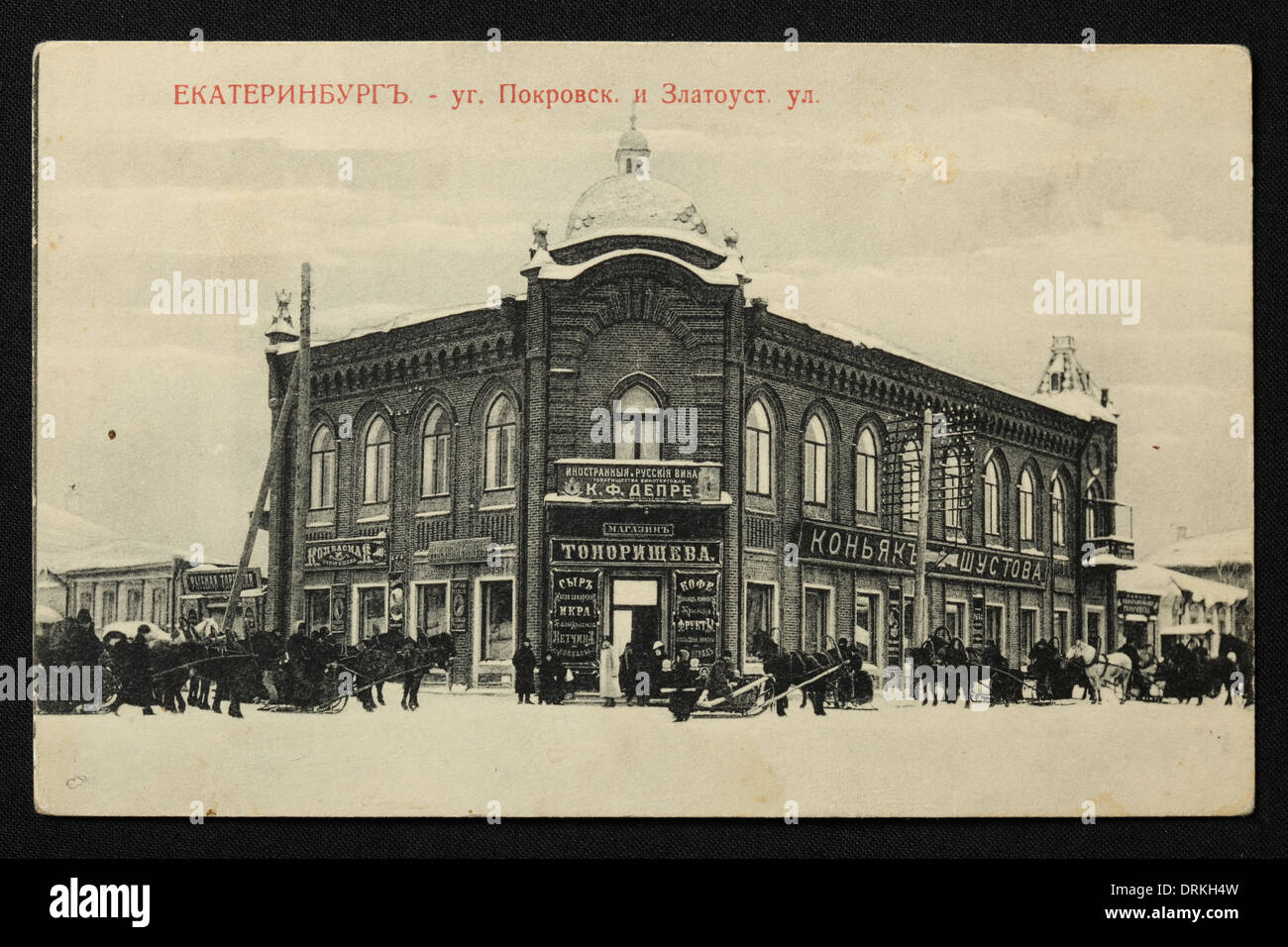 Toporishchev Grocery Store and Shustov Cognac Store in Pokrovsky Prospekt Avenue in Yekaterinburg, Russian Empire. Black and white vintage photograph by Russian photographer Nikolai Vvedensky dated from the beginning of the 20th century issued in the Russian vintage postcard published by M.S. Semkov, Yekaterinburg. Text in Russian: Yekaterinburg. Conner of Pokrovsky Prospekt Avenue and Zlatoustovskaya Street. Winter scene. Courtesy of the Azoor Postcard Collection. Stock Photo